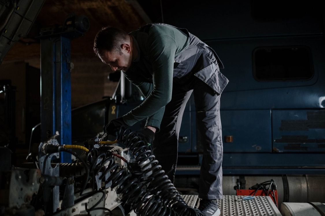 Mechanic working on vehicle engine components in a workshop