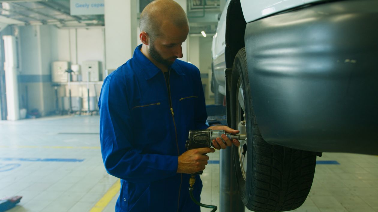 Mechanic using an impact wrench to service a car wheel